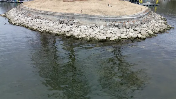Rip rap armoring a curved shoreline below a seawall